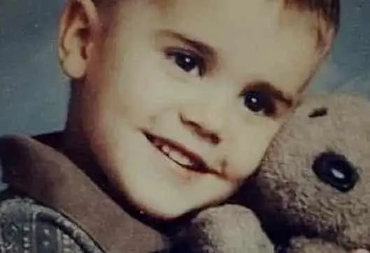 A smiling Justin Bieber alongside his beloved teddy.
