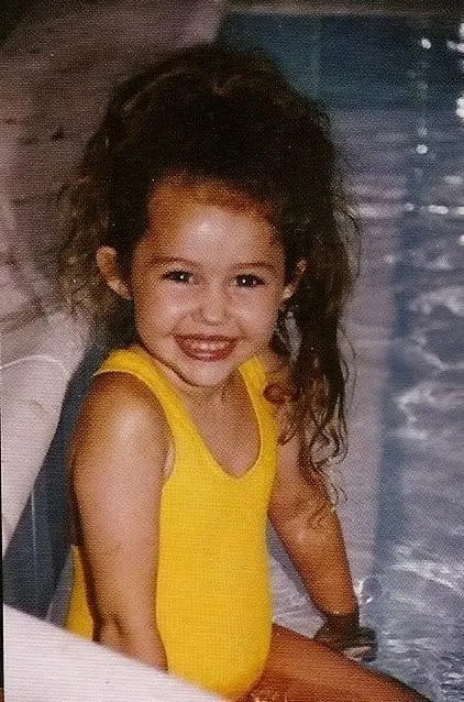 Young Miley Cyrus, smiling to the camera.