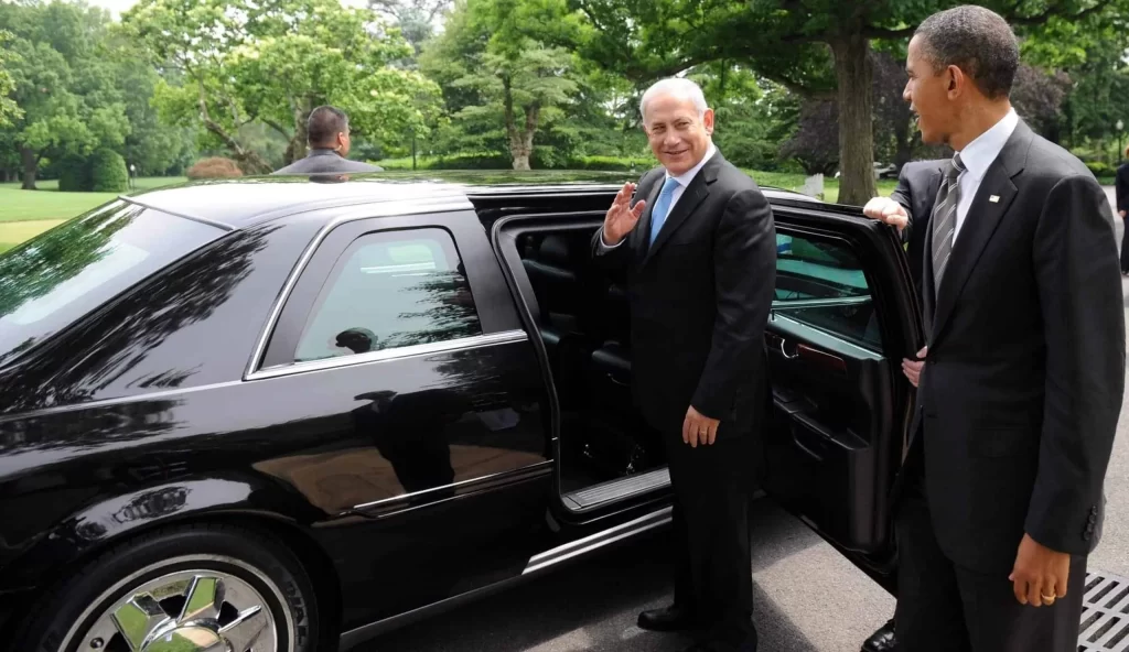 Benjamin Netanyahu stands beside his official car and bids farewell to Barack Obama.