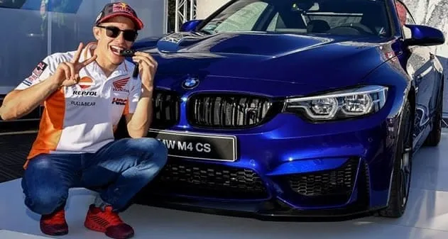 Marc Marquez posing next to his BMW M4 CS.