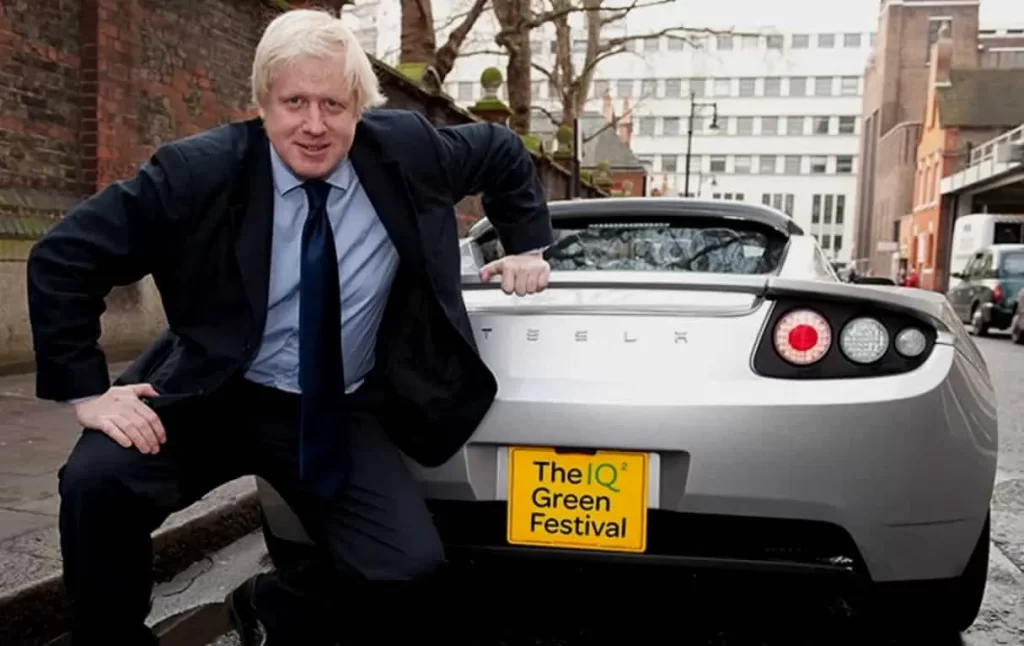 Boris Johnson posing next to his Tesla Roadster.