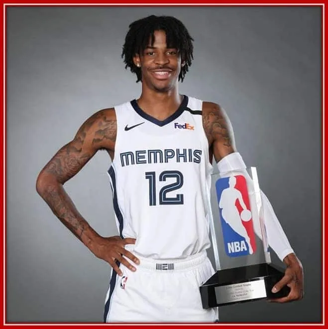 Behold the 2019 NBA Rookie of the Year, Ja Morant, as he Holds Closely his Trophy.