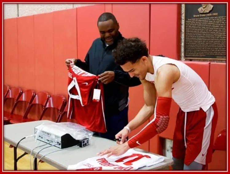 Trae Young is Standing Alongside his Father as he Signs an Autograph.